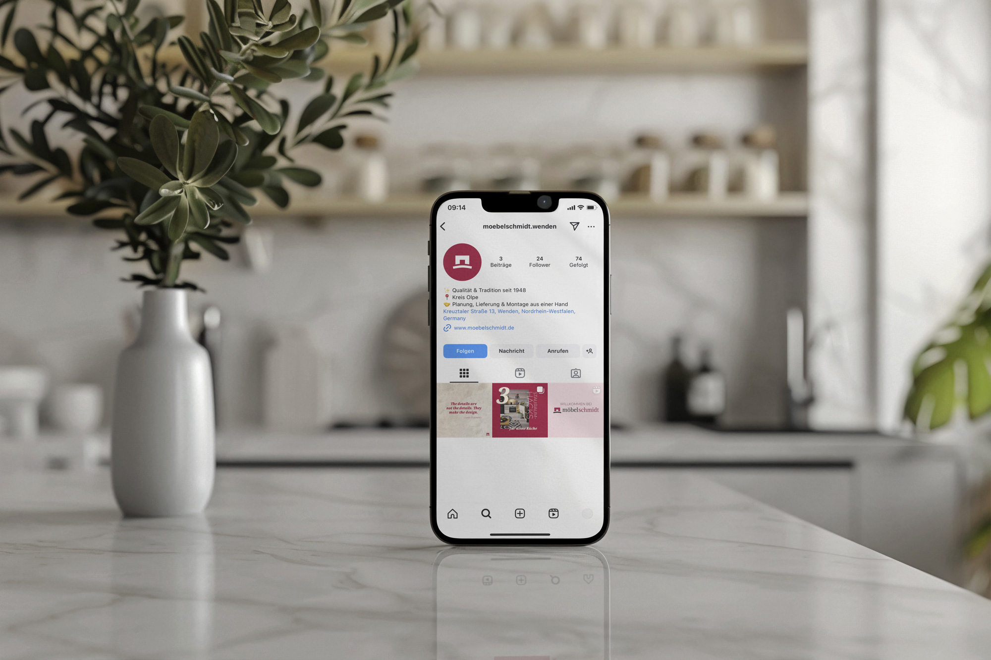 Smartphone&#x20;auf&#x20;einer&#x20;Marmorarbeitsfl&#xE4;che&#x20;zeigt&#x20;das&#x20;Instagram-Profil&#x20;von&#x20;&quot;moebelschmidt.wenden&quot;&#x20;in&#x20;einer&#x20;modernen&#x20;K&#xFC;che&#x20;mit&#x20;wei&#xDF;er&#x20;Vase&#x20;und&#x20;Gr&#xFC;npflanze&#x20;im&#x20;Hintergrund.